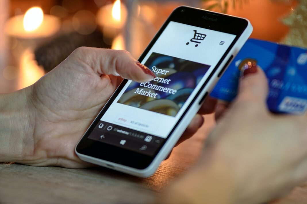 person-using-black-and-white-smartphone-and-holding-blue-230544 using online shopping app