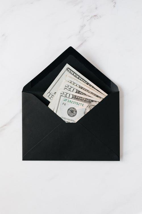 Black envelope with cash dollars on marble table
