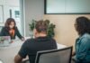 6 Pillars of Successful Client Communication Black employee talking to multiethnic clients at table in office