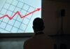 What is a Good IRR man wearing white top looking at projector graph screen