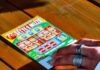 A Brief History of Scratchcards person in white long sleeve shirt holding white and red box