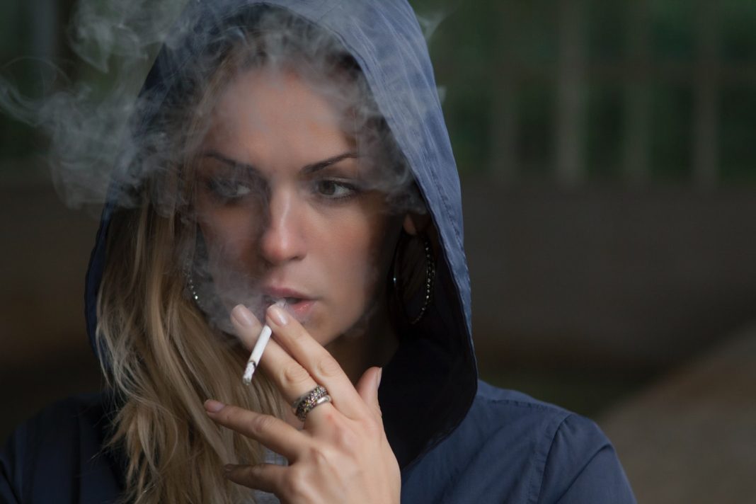 Photo by Stas Svechnikov woman wearing hoodie while holding cigarette