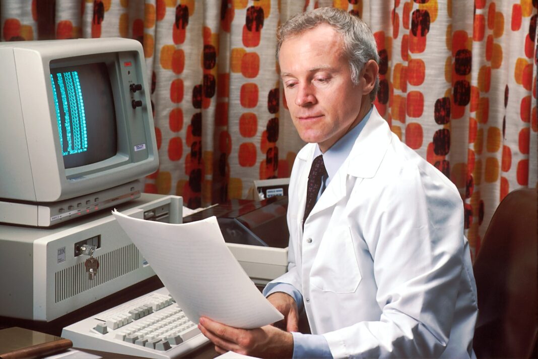 Photo by National Cancer Institute man reading papers in front of computer