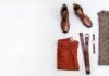 10 Wardrobe Essentials for Most Men pair of brown leather boots, red shorts, brown leather belt, round gold-colored watch, and brown top