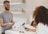 7 Ways to Optimize Your Service Business man in grey crew-neck t-shirt smiling to woman on counter