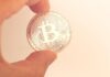 How Does Bitcoin Change Your Life? Fingers Holding Round Silver Coin