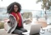 Online Betting in India, How to Choose the Best Happy excited African American female laughing and gesticulating while having video calling on laptop and sitting at modern cafe
