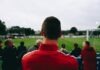 The pros and cons of cash-out in sports betting man standing while watching soccer during daytime