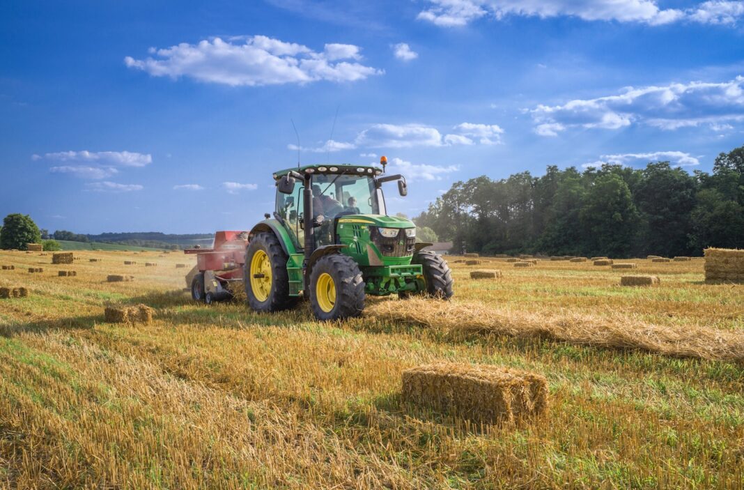 Photo by Randy Fath green tractor on brown grass field under blue sky during daytime