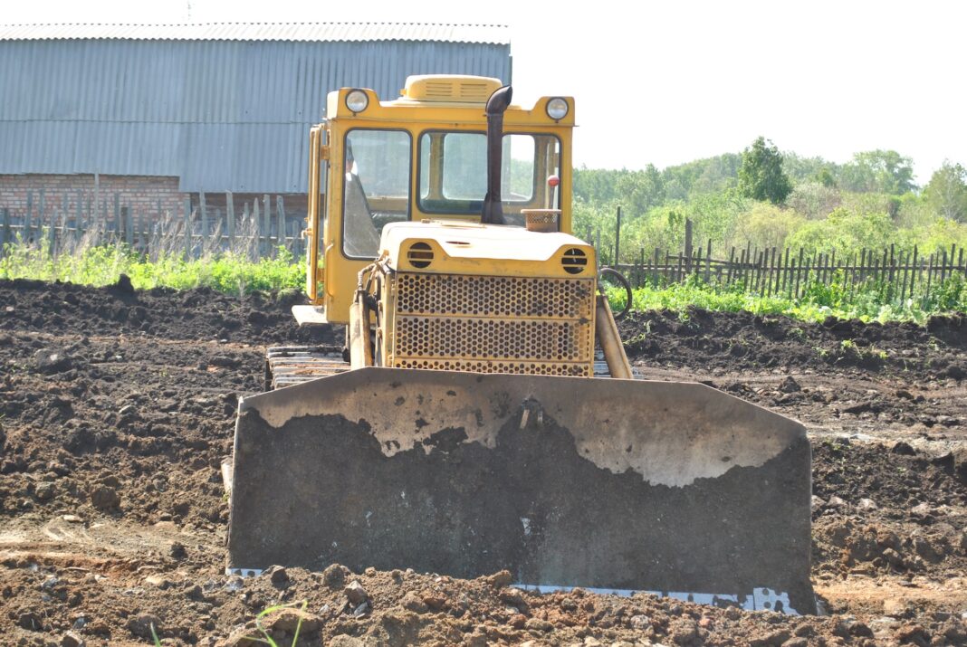 Photo by Bermix Studio a bulldozer is sitting in the middle of a field