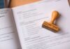 Errors in documents and mobile notary services brown wooden hand tool on white printer paper
