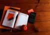 black scientific calculator, orange, and notebook on table