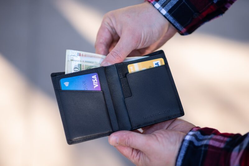 Photo by Emil Kalibradov black leather bifold wallet on persons hand