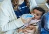 Holle Goat Milk Formula: The Perfect Alternative to Breast Milk High angle of crop mother embracing little African American baby and feeding from bottle sitting on sofa near son