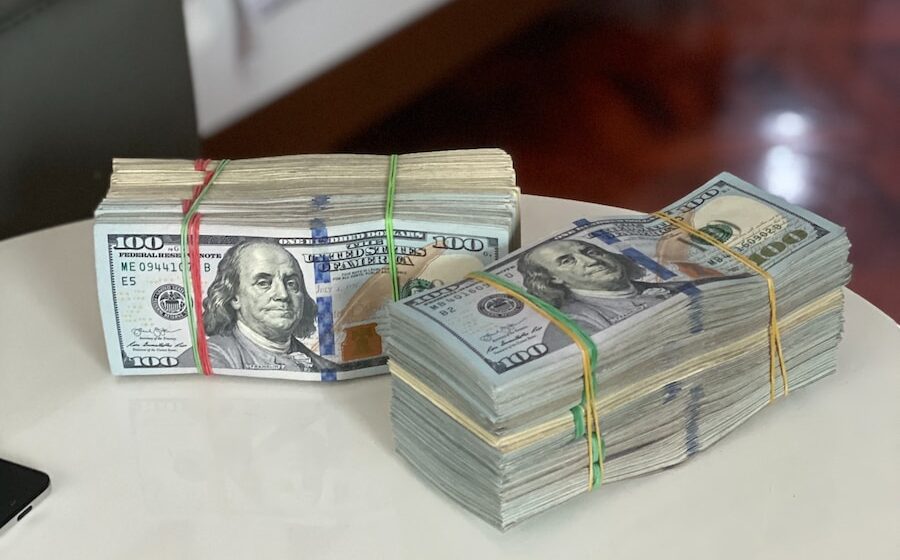 Photo by Celyn Kang a stack of money sitting on top of a white table