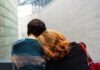 Are You In A Financially Abusive Relationship? a woman rests her head on another person's shoulder