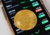 BlockBinding Bulletins: Unifying Bitcoin with Notable Cryptocurrencies Gold Round Coin on Top of a Cellphone