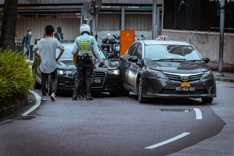 Photo by C Joyful man in white and black stripe shirt and black pants standing beside black car during daytime