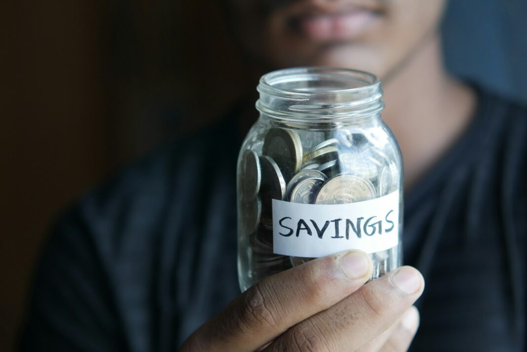 Photo by Towfiqu barbhuiya a man holding a jar with a savings label on it