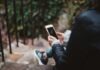 person holding white smartphone sitting on stair