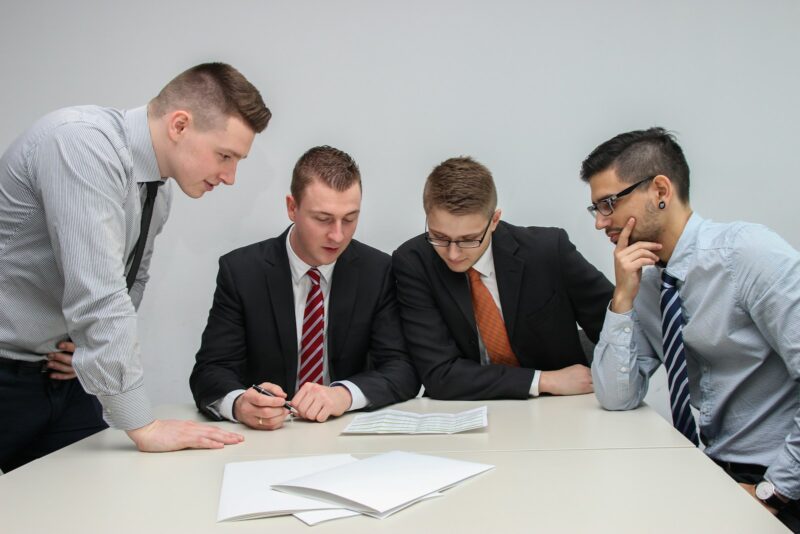Photo by Sebastian Herrmann four men looking to the paper on table