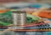 Seminars Providing Key Insights into Behavioral Finance Strategies A stack of coins on top of various colored banknotes, symbolizing finance and currency.