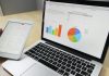 Maximizing ROI: Where to Spend and Where to Save in Your Business Laptop displaying charts and graphs with tablet calendar for data analysis and planning.