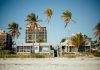 Three Critical Factors to Consider Before Purchasing a Beach Home in Italy Sunny beachfront view with palm trees and modern houses, perfect for a tropical getaway.