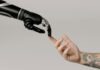 The Role of AI in Shaping the Future of Investment Banking A human hand with tattoos reaching out to a robotic hand on a white background.