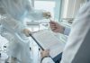 Think You’re Healthy? Why You Still Need International Health Insurance A doctor hands a clipboard to a patient for signature, highlighting medical professionalism.