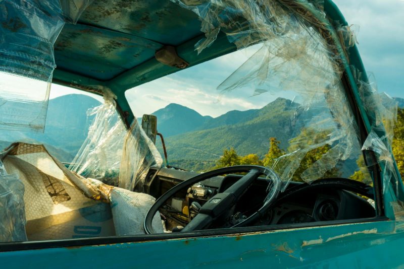 Photo by mali maeder Old rusty truck with broken windows in front of mountain landscape, symbolizing decay.