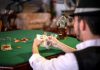 Gamble at Your Own Risk A man holding a poker hand at a casino table with chips and whiskey, conveying a gambling atmosphere.