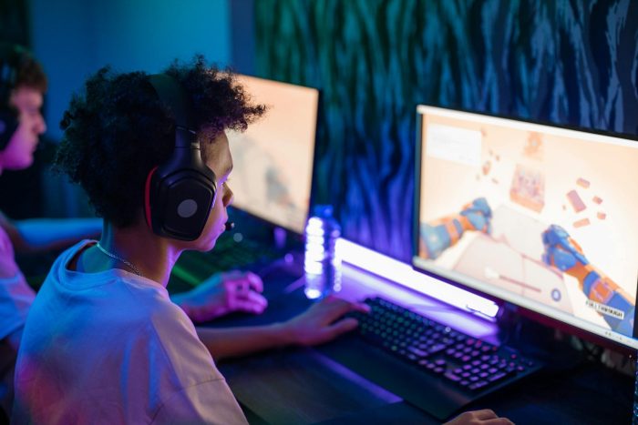 Photo by Ron Lach Teen gamers engrossed in online computer game in a vibrant, modern gaming room.