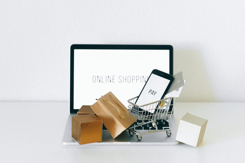 Photo by Nataliya Vaitkevich Display of online shopping theme with mini cart and payment devices on laptop.