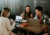 Earn a Lot of Money by Studying Abroad: Top Courses to Achieve Millionaire Status three people sitting in front of table laughing together