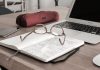 The Hidden Costs of Managing Finances In-House: When to Consider Outsourcing eyeglasses on book beside laptop