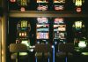 The Best Ancient Civilization-Themed Slots and Their Features Slot machines in a dimly lit casino with reflective ceiling and empty chairs.