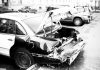 How Is Compensation Calculated in a Car Accident Claim? A black and white photo of a wrecked car on an urban street, highlighting vehicle damage.