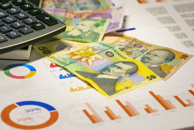 Photo by Jakub Żerdzicki A calculator sitting on top of a pile of money