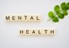 the word mental health spelled with scrabbles next to a green leaf