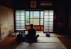 Japan’s Minimalist Lifestyle: What Travelers Can Learn A person meditating in a tranquil traditional Japanese room, facing the view outside.