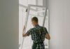 A professional installer fitting a modern window in a well-lit home interior.