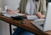 Decoding The Statute Of Limitations On Debt A woman manages finances at home, using a laptop and calculator on a wooden desk.