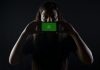 How to Transfer WhatsApp on a New Phone woman holding black smartphone at Whatsapp logo