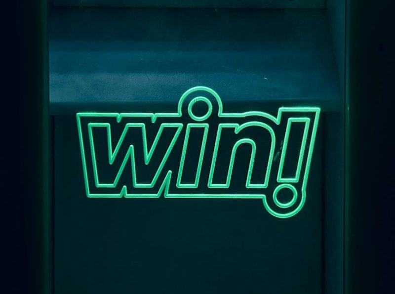 Photo by Alejandro Pérez a neon sign with the word win on it