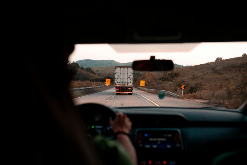 Photo by UHGO Scenic drive with a truck on a highway surrounded by hills. Perfect for travel themes.