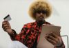 How to Protect Your Credit Card from Fraud and Scams Fashionable individual with afro hair using a tablet and credit card for online shopping indoors.