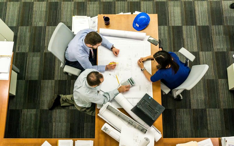Photo by Pixabay Top view of a team working on construction plans in an office setting.