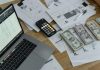 Payroll Pricing Demystified: How to Choose the Right Provider Without Surprises A desk with financial documents, currency, a laptop, and phone calculator.