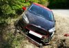 Are Car Accidents More Common Today Than a Few Years Ago? A black car, seemingly a Ford, crashed and damaged in a roadside ditch with surrounding greenery.